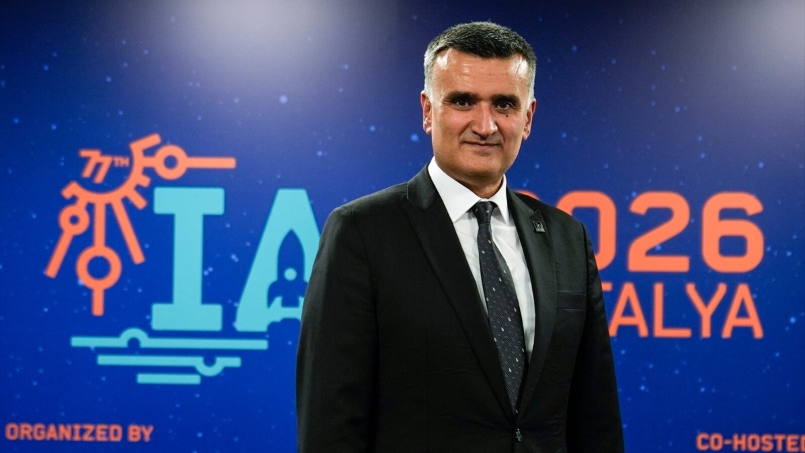 ODTÜ Rektörü Prof. Dr. Ahmet Yozgatlıgil IAC 2026 logosu önünde